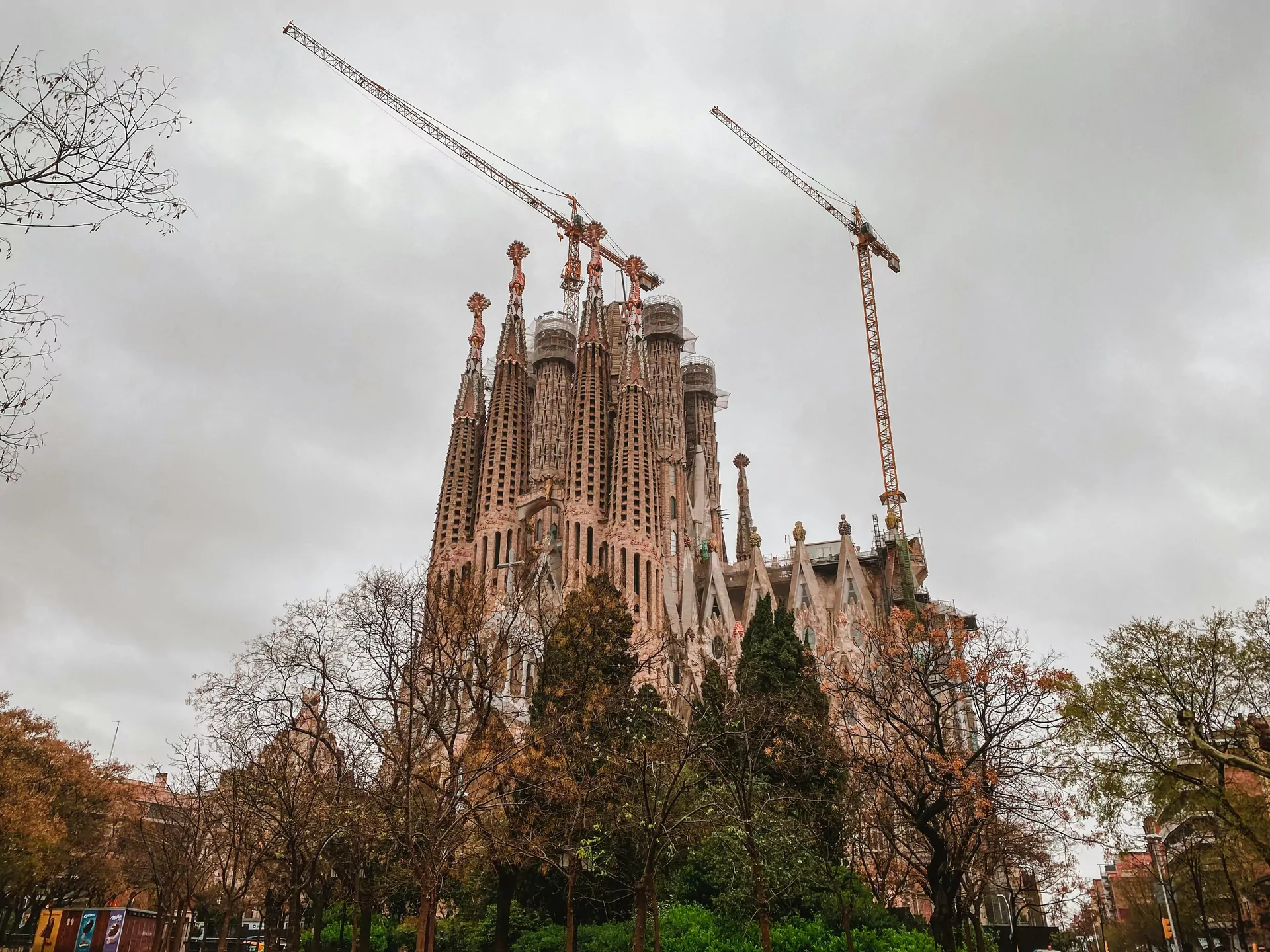 Sagrada Família z zewnątrz, kościół góruje nad fotografem i drzewami, obok dźwig