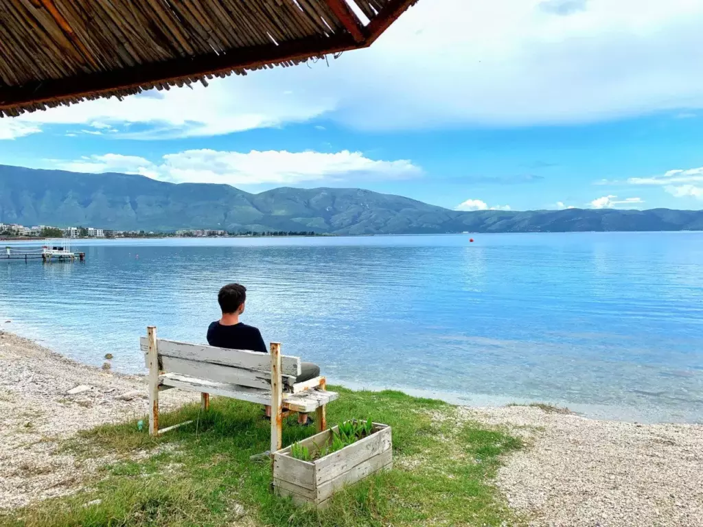 Albania Bartek siedzi na ławce nad wodą